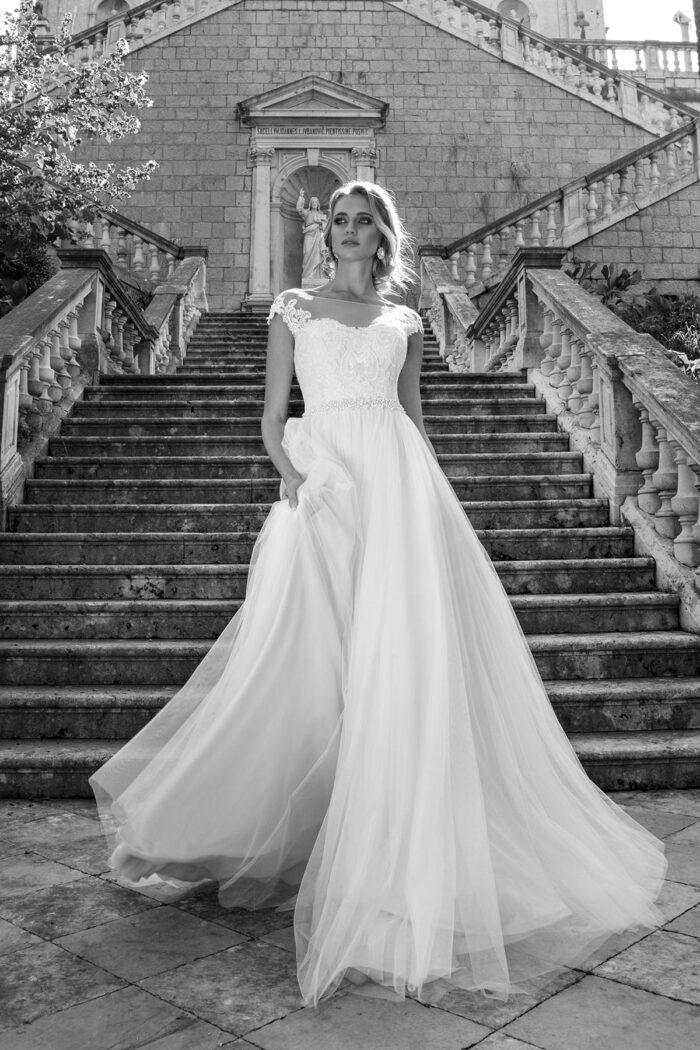 Mia 15906 4 Lussano Воздушное свадебное платье молочного оттенка создано для романтичны невест для свадьбы на природе или на берегу моря! Аккуратный верх корсета украшен венецианскими аппликациями молочного цвета, которые создают фигурные очертания соблазнительного выреза и плеч, пояс из мерцающих камней и стразов подчеркивает тонкую талию, спинка платья с вырезом, подчеркивающим красивую спину и осанку невесты. Невесомая и легкая тюльмариновая юбка сзади переходит в небольшой шлейф.