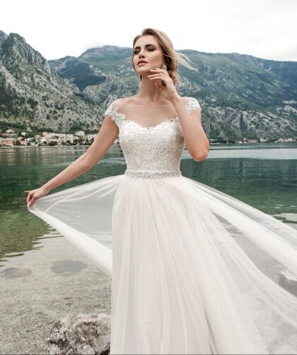 Mia 15906 - Lussano Mia 15906 3 Lussano Воздушное свадебное платье молочного оттенка создано для романтичны невест для свадьбы на природе или на берегу моря! Аккуратный верх корсета украшен венецианскими аппликациями молочного цвета, которые создают фигурные очертания соблазнительного выреза и плеч, пояс из мерцающих камней и стразов подчеркивает тонкую талию, спинка платья с вырезом, подчеркивающим красивую спину и осанку невесты. Невесомая и легкая тюльмариновая юбка сзади переходит в небольшой шлейф.