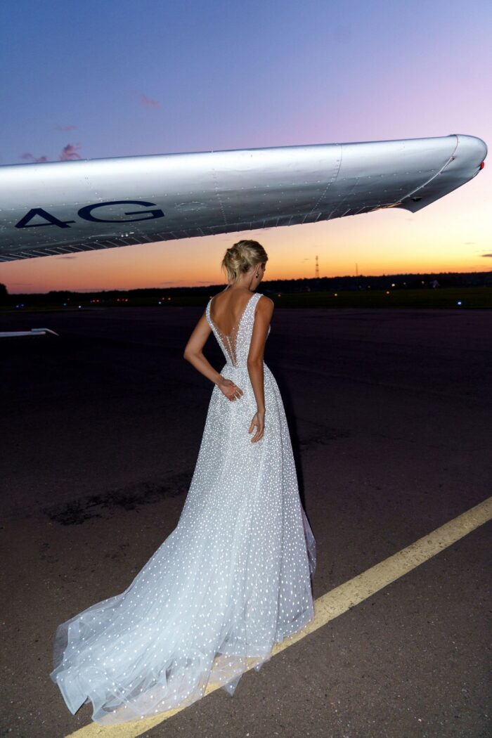 Келли 3 Наталья Романова Сделайте свой особый день ярче с нашим изысканным свадебным платьем А-силуэта. Это платье с привлекательным V-образным вырезом спереди, по бокам и открытой спиной позволит вам выглядеть и чувствовать себя принцессой. Изготовленный из роскошного тюля и сверкающих блесток, он станет идеальным выбором!