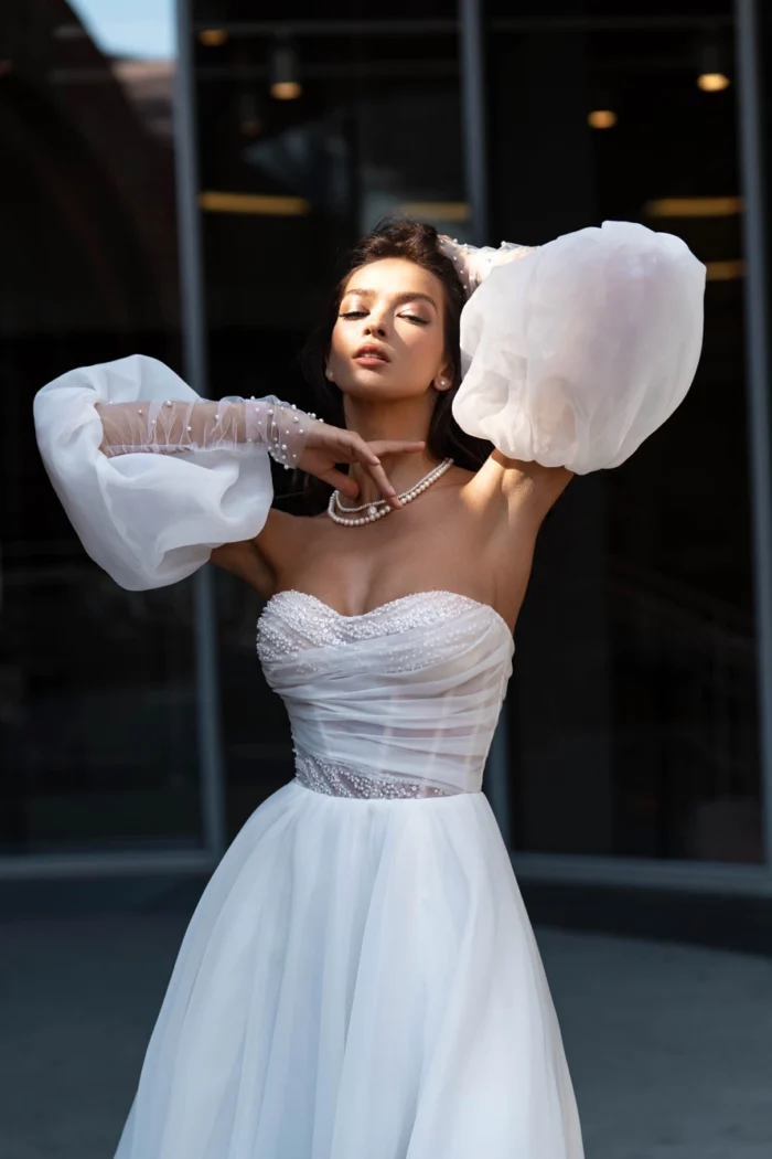 Джитта 2 Сонеста <p style="text-align: justify;">Свадебном платье, которое проникнуто чувственностью и глубокой романтикой. Это восхитительное свадебное платье А-силуэта является воплощением элегантности и изящества. Оно обладает прекрасными съёмными рукавами, которые добавляют утонченности вашему образу, разрез в юбке создаёт изысканную игру скрытых желаний. Этот неповторимый наряд украшен яркими жемчужинами, которые придают ему изысканность и блеск. Корсет и рукава, украшенные этими роскошными жемчужинами, создают волшебное сочетание, словно звёзды на ночном небе. Рукава раздельные, что дарит вам выбор и возможность подчеркнуть вашу нежность и изящество, надев только баффы или только перчатки с жемчужинами. Основной материал этого прекрасного платья - органза, придает ему легкость и нежность. Этот материал словно облачает вас в волшебное облако, лаская и приковывая взгляды своей изысканностью. Подарите себе особое волшебство и сладкую мечту о романтическом свадебном торжестве с этим шедевром рукотворного искусства.</p>
<iframe src="https://www.youtube.com/embed/uXVNwrSMwT4" width="auto" height="600" frameborder="0" allowfullscreen="allowfullscreen"></iframe>