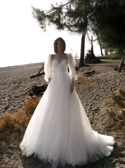 Лотти 1 Наталья Романова Любовь витает в воздухе, и это роскошное свадебное платье подходит для принцессы. Изысканное платье А-силуэта из струящегося тюля и кружева с эффектным V-образным вырезом и многочисленными многослойными оборками на юбке имеет тонкий лиф с длинными съемными рукавами. Спина на внутреннем корсете отделана кружевными аппликациями, которые создают поразительный силуэт.