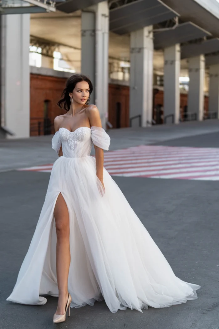 Николетта 3 Сонеста <p style="text-align: justify;">В пленительном облаке фатина искусно вышитого лифа, это свадебное платье А-силуэта вобрало в себя элегантность и современный романтизм. Его разрез в юбке придает образу невесты изысканную изящность и провокационную нотку. Лиф этого завораживающего творения окутывает тело в форме сердечка, пленяя внимание и обрамляя декольте нежной россыпью вышитых деталей. Можно выбрать стиль с бретелями, которые спускаются нежно и провокационно по плечам, или с объемными рукавами-баффами, добавляющими оригинальности и элегантности образу. Главной фантазией платья является его основной материал - фатин. Он создает вуальную легкость и непринужденность, позволяя невесте свободно двигаться и чувствовать себя легкой, как перышко. Это платье - объятие современного романтизма и элегантности, идеально подходящее для невесты, мечтающей о воплощении своего любовного сказочного идеала.</p>
<iframe src="https://www.youtube.com/embed/F7HGvGtQNrU" width="auto" height="600" frameborder="0" allowfullscreen="allowfullscreen"></iframe>