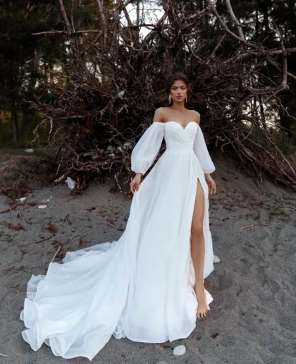 Роберта - Наталья Романова Роберта 1 Наталья Романова Испытайте романтику и красоту, как никогда раньше, с нашим потрясающим свадебным платьем А-силуэта с открытыми плечами! Это изысканное платье с длинными рукавами-фонариками и разрезом на юбке выполнено из красивого шифона. Убедитесь, что ваш особенный день станет незабываемым с этим идеальным свадебным образом.