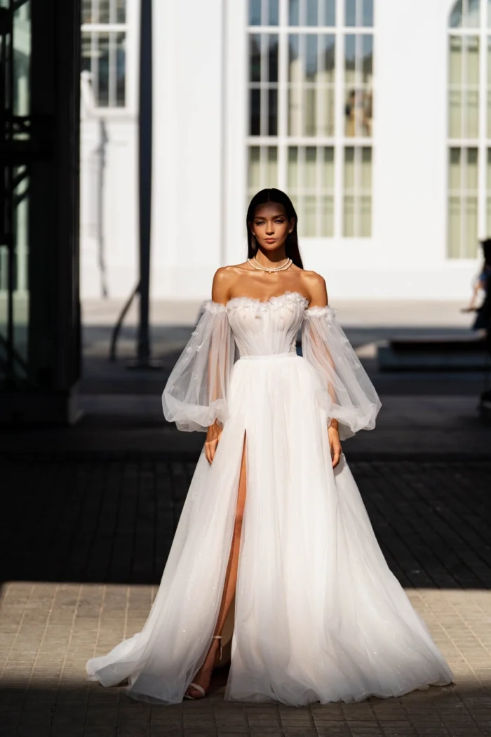 Ума 1 Сонеста <p style="text-align: justify;">Свадебном платье, которое словно вышло из самых прекрасных сновидений и станет воплощением твоей романтической мечты. Это изящное платье А-силуэта привлекает внимание с первого взгляда, благодаря его блестящей подкладке, которая словно звездное небо на твоем свадебном пути. Разрез в юбке добавляет шарма и позволит тебе медленно шагая по проложенной дорожке, оставлять восхитительные следы своего счастливого венчания. Но самая восхитительная деталь этого платья – его украшение цветами. Каждый цветочек, расшитый с большой тщательностью, наполняет платье нежностью и элегантностью. Огромные объемные съемные рукава создают образ невероятной легкости и изысканности, словно облака, позволяя тебе плавно скользить под арками торжественных залов во время своего величественного входа. Это платье – отражение мечты о вечной любви и романтике. Оно идеально подчеркнет нежность и женственность, и каждый шаг в нем будет наполнен красотой и эмоциональным волнением.</p>
<iframe src="https://www.youtube.com/embed/Sy9zdeGbnoI" width="auto" height="600" frameborder="0" allowfullscreen="allowfullscreen"></iframe>