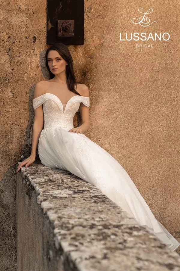 Rosemary 21042 1 Lussano Свадебное платье силуэта принцесса с мерцающей юбкой и утонченным декором. Корсет со шнуровкой на спине и вырезом «сердечко» дополняют спущенные бретели, открывающие плечи. Верх платья декорирован кружевными аппликациями, а талия акцентирована тонким поясом. Многослойная пышная юбка выполнена из фатина, покрытого мелкими переливающимися блестками.