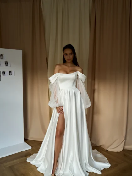 Эрма 1 Сониа Солей <p style="text-align: justify;">Свадебное платье А-силуэта со спущенными бретелями и объемными съемными рукавами представляет собой идеальный выбор для невесты, которая желает выглядеть элегантно и романтично в свой особенный день. Изготовленное из высококачественного атласа и фатина, это платье обладает прекрасной структурой и легкостью. Безупречно подогнанное по фигуре, оно ласкает формы женского тела, придавая изящность силуэту. Платье имеет интересный дизайн со спущенными бретелями, которые придают ему нежность и воздушность. Плечи свободны, что позволяет невесте чувствовать себя комфортно и свободно в течение всего мероприятия. Особенностью этого платья являются объемные съемные рукава, которые придают наряду одновременно элегантный и изысканный вид. Вы можете выбрать, оставить их на платье или снять во время танцев и веселья. Юбка платья с разрезом добавляет изюминку и позволяет выглядеть более изящно при каждом шаге. Закрытая спинка на молнии обеспечивает легкость и удобство при одевании и снятии платья. Общая эстетика и качество материалов делают это свадебное платье отличным выбором для всех типов фигуры и стилей свадьбы. Оно гарантирует, что вы будете выглядеть роскошно и неповторимо в свой самый важный день жизни.</p>
<iframe src="https://www.youtube.com/embed/Sz5DpFmTi6c" width="auto" height="600" frameborder="0" allowfullscreen="allowfullscreen"></iframe>