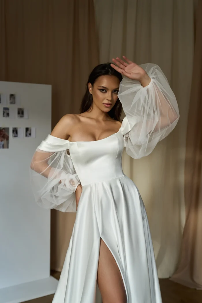 Эрма 1 Сониа Солей <p style="text-align: justify;">Свадебное платье А-силуэта со спущенными бретелями и объемными съемными рукавами представляет собой идеальный выбор для невесты, которая желает выглядеть элегантно и романтично в свой особенный день. Изготовленное из высококачественного атласа и фатина, это платье обладает прекрасной структурой и легкостью. Безупречно подогнанное по фигуре, оно ласкает формы женского тела, придавая изящность силуэту. Платье имеет интересный дизайн со спущенными бретелями, которые придают ему нежность и воздушность. Плечи свободны, что позволяет невесте чувствовать себя комфортно и свободно в течение всего мероприятия. Особенностью этого платья являются объемные съемные рукава, которые придают наряду одновременно элегантный и изысканный вид. Вы можете выбрать, оставить их на платье или снять во время танцев и веселья. Юбка платья с разрезом добавляет изюминку и позволяет выглядеть более изящно при каждом шаге. Закрытая спинка на молнии обеспечивает легкость и удобство при одевании и снятии платья. Общая эстетика и качество материалов делают это свадебное платье отличным выбором для всех типов фигуры и стилей свадьбы. Оно гарантирует, что вы будете выглядеть роскошно и неповторимо в свой самый важный день жизни.</p>
<iframe src="https://www.youtube.com/embed/Sz5DpFmTi6c" width="auto" height="600" frameborder="0" allowfullscreen="allowfullscreen"></iframe>