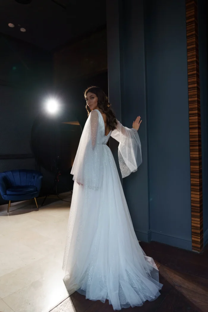 Ева 3 Сониа Солей <p style="text-align: justify;">Свадебное платье Ева А-силуэта - это идеальный выбор для невест, которые хотят выглядеть элегантно и впечатляюще в свой важный день. Это платье имеет V-образный вырез, который подчеркивает красоту шеи и груди, придавая образу нежности и женственности. Но самым впечатляющим элементом этого платья являются объемные крылья на плечиках, которые создают эффектное и роскошное ощущение. Они придают платью небесный и легкий вид, как будто невеста летит под венец. Спинка платья застегивается на молнии, что обеспечивает удобное и легкое надевание. Это позволяет невесте чувствовать комфорт на протяжении всего свадебного мероприятия. Основной материал, используемый в этом платье, - это фатин. Фатин - легкая, но одновременно элегантная ткань, которая создает воздушное и романтичное ощущение. В сочетании с глиттером, этот материал придает платью блеск и сияние, подчеркивая изысканность и роскошь внешнего вида. Свадебное платье Ева А-силуэта с V-образным вырезом и объемными крыльями на плечах является уникальным и неповторимым выбором для невесты, которая хочет быть обрамленной грацией и роскошью в свой великий день.</p>
<iframe src="https://www.youtube.com/embed/_WmakzHHiM0" width="auto" height="600" frameborder="0" allowfullscreen="allowfullscreen"></iframe>