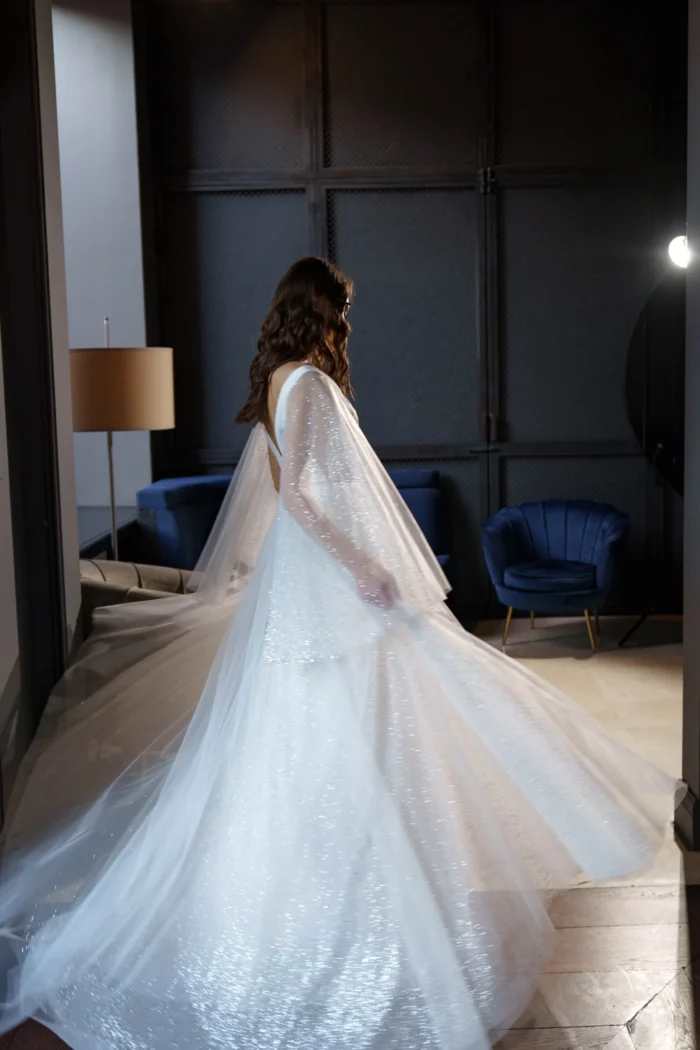 Ева 1 Сониа Солей <p style="text-align: justify;">Свадебное платье Ева А-силуэта - это идеальный выбор для невест, которые хотят выглядеть элегантно и впечатляюще в свой важный день. Это платье имеет V-образный вырез, который подчеркивает красоту шеи и груди, придавая образу нежности и женственности. Но самым впечатляющим элементом этого платья являются объемные крылья на плечиках, которые создают эффектное и роскошное ощущение. Они придают платью небесный и легкий вид, как будто невеста летит под венец. Спинка платья застегивается на молнии, что обеспечивает удобное и легкое надевание. Это позволяет невесте чувствовать комфорт на протяжении всего свадебного мероприятия. Основной материал, используемый в этом платье, - это фатин. Фатин - легкая, но одновременно элегантная ткань, которая создает воздушное и романтичное ощущение. В сочетании с глиттером, этот материал придает платью блеск и сияние, подчеркивая изысканность и роскошь внешнего вида. Свадебное платье Ева А-силуэта с V-образным вырезом и объемными крыльями на плечах является уникальным и неповторимым выбором для невесты, которая хочет быть обрамленной грацией и роскошью в свой великий день.</p>
<iframe src="https://www.youtube.com/embed/_WmakzHHiM0" width="auto" height="600" frameborder="0" allowfullscreen="allowfullscreen"></iframe>