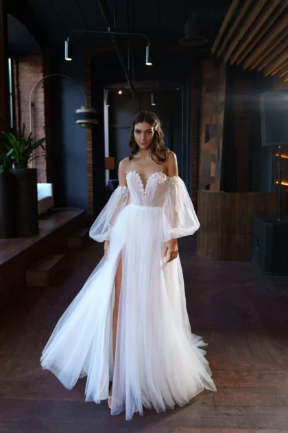 Кейси 1 Сониа Солей <p style="text-align: justify;">Свадебное платье Кейси - это изящное и романтичное платье, которое подчеркнет вашу женственность в самый важный день вашей жизни. Оно имеет элегантный А-силуэт, который плавно обтекает талию и бедра, подчеркивая вашу фигуру. Это платье имеет несколько особенностей, которые делают его неповторимым. Оно оснащено съемными объемными рукавами, что позволяет вам изменить образ в течение дня. Рукава украшены кружевными деталями, придающими им воздушный и роскошный вид. Юбка платья имеет разрез, который добавляет изюминку и позволяет вам свободно двигаться. Основной материал, используемый для этого платья, - это фатин, который придает платью легкость и пышность. Кружевные вставки на платье дополняют его элегантным и романтичным стилем. Свадебное платье Кейси - идеальный выбор для тех, кто хочет выглядеть изысканно и привлекательно в свой особый день. Оно подойдет для различных тематических свадеб и стилей, от классических до более современных.</p>
<iframe src="https://www.youtube.com/embed/hSK7u7-qrZQ" width="auto" height="600" frameborder="0" allowfullscreen="allowfullscreen"></iframe>