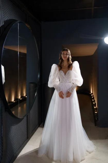 Ливия 1 Сониа Солей <p style="text-align: justify;">Свадебное платье Ливия - это изящное и романтичное платье в стиле А-силуэта, созданное для создания неповторимого образа невесты. Оно имеет объемные рукава и спинку на внутреннем корсете со шнуровкой и пуговичками, что придает ему особую изысканность. Основной материал этого платья - фатин, который придает ему легкость и воздушность. Кружево, используемое в дизайне платья, добавляет ему элегантности и изысканности, подчеркивая женственные черты невесты. Органза в платье придает ему объем и дополнительную игривость. Свадебное платье Ливия прекрасно подойдет для невесты, которая хочет выглядеть изысканно и неповторимо в свой особенный день. Его дизайн и материалы создадут воздушный и элегантный образ, который будет запоминаться на долгое время.</p>
<iframe src="https://www.youtube.com/embed/2vvifKydu4I" width="auto" height="600" frameborder="0" allowfullscreen="allowfullscreen"></iframe>