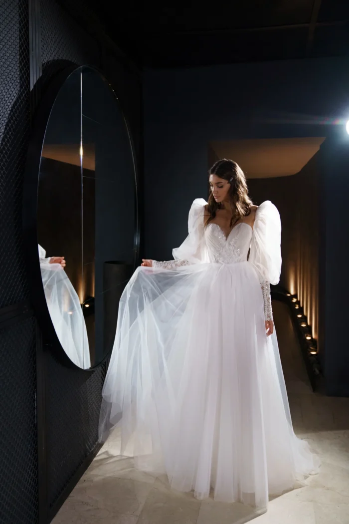 Ливия - Сониа Солей Ливия 3 Сониа Солей <p style="text-align: justify;">Свадебное платье Ливия - это изящное и романтичное платье в стиле А-силуэта, созданное для создания неповторимого образа невесты. Оно имеет объемные рукава и спинку на внутреннем корсете со шнуровкой и пуговичками, что придает ему особую изысканность. Основной материал этого платья - фатин, который придает ему легкость и воздушность. Кружево, используемое в дизайне платья, добавляет ему элегантности и изысканности, подчеркивая женственные черты невесты. Органза в платье придает ему объем и дополнительную игривость. Свадебное платье Ливия прекрасно подойдет для невесты, которая хочет выглядеть изысканно и неповторимо в свой особенный день. Его дизайн и материалы создадут воздушный и элегантный образ, который будет запоминаться на долгое время.</p>
<iframe src="https://www.youtube.com/embed/2vvifKydu4I" width="auto" height="600" frameborder="0" allowfullscreen="allowfullscreen"></iframe>