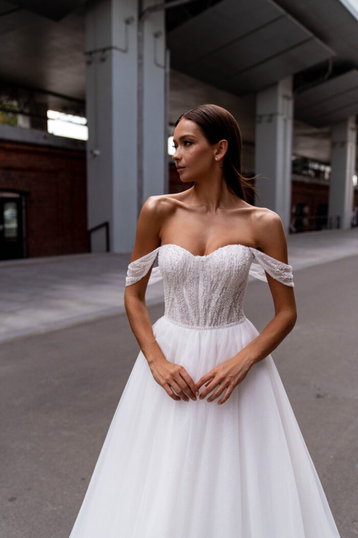 Сибилл 3 Сонеста <p style="text-align: justify;">Романтическое свадебное платье, которое сияет светом любви и мечты. Это прекрасное свадебное платье А-силуэта, созданное с использованием самых изысканных материалов, чтобы вы сияли на своем особенном дне. Изящный фатин, подобно нежному облачку нежности, обрамляет вашу фигуру, придавая ей легкость и воздушность. А блестящая подкладка, легко просвечивая сквозь фатин, словно придаёт вашему образу загадочный и сказочный блеск. Корсет платья – настоящее произведение искусства. Он расшит бисером с нежными цветочными узорами, которые исторгаются в свете сияющих кристаллов и создают игру света и тени на вашем плече и линии декольте. Эти ослепительные детали подчеркивают вашу женственность и придают вашему облику особый шарм. Созданное с любовью и заботой, это платье излучает романтику и мечту. Оно захватывает душу своей изысканностью и притягивает взгляды всех присутствующих. В нем каждая ваша прогулка к алтарю будет напоминать танец на облаках, а каждый миг будет запечатлен в памяти, как самая романтическая глава вашей истории любви.</p>
<iframe src="https://www.youtube.com/embed/UIyJ7qy7jto" width="auto" height="600" frameborder="0" allowfullscreen="allowfullscreen"></iframe>