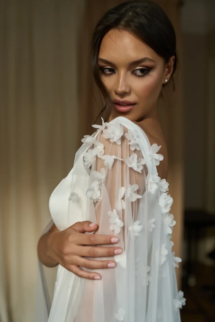 Долорес 2 Сониа Солей Это свадебное платье подчеркивает фигуру невесты благодаря облегающему силуэту и широким бретелям. Спинка платья застегивается на молнию, что обеспечивает удобство и комфорт. Платье выполнено из тонкого атласа, который придает ему элегантность и блеск. Для создания романтического образа можно добавить съемный кейп из фатина, украшенный 3D цветами. Кейп легко крепится к платью и создает эффект пышной юбки. Цвет платья - молочный, что подходит для светлых и темных типов кожи.
<iframe src="https://www.youtube.com/embed/VXE2VoEbQ0g" width="auto" height="600" frameborder="0" allowfullscreen="allowfullscreen"></iframe>