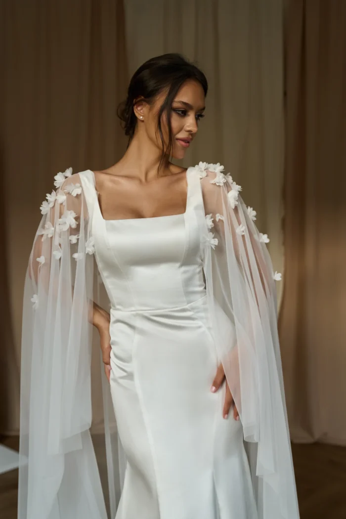 Долорес 1 Сониа Солей Это свадебное платье подчеркивает фигуру невесты благодаря облегающему силуэту и широким бретелям. Спинка платья застегивается на молнию, что обеспечивает удобство и комфорт. Платье выполнено из тонкого атласа, который придает ему элегантность и блеск. Для создания романтического образа можно добавить съемный кейп из фатина, украшенный 3D цветами. Кейп легко крепится к платью и создает эффект пышной юбки. Цвет платья - молочный, что подходит для светлых и темных типов кожи.
<iframe src="https://www.youtube.com/embed/VXE2VoEbQ0g" width="auto" height="600" frameborder="0" allowfullscreen="allowfullscreen"></iframe>