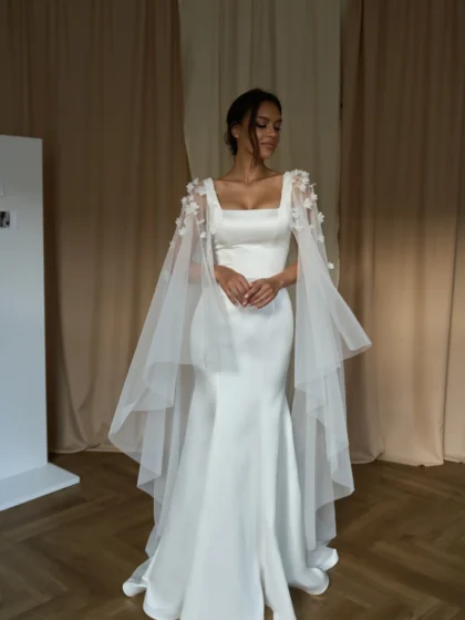 Долорес 1 Сониа Солей Это свадебное платье подчеркивает фигуру невесты благодаря облегающему силуэту и широким бретелям. Спинка платья застегивается на молнию, что обеспечивает удобство и комфорт. Платье выполнено из тонкого атласа, который придает ему элегантность и блеск. Для создания романтического образа можно добавить съемный кейп из фатина, украшенный 3D цветами. Кейп легко крепится к платью и создает эффект пышной юбки. Цвет платья - молочный, что подходит для светлых и темных типов кожи.
<iframe src="https://www.youtube.com/embed/VXE2VoEbQ0g" width="auto" height="600" frameborder="0" allowfullscreen="allowfullscreen"></iframe>