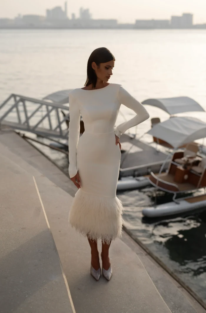 Диджи 2 1 Martha (Марта) <p style="text-align: justify;">Свадебное платье облегающего силуэта длины миди с длинными рукавами. Основной материал - креп, который придает элегантность и лаконичность наряду. Декор из перьев добавляет изысканности и легкости образу невесты. Длинные рукава и миди-длина делают платье скромным и женственным. В целом, это элегантный и стильный вариант для невесты. Такое платье подчеркнет фигуру и придаст образу нежности и романтичности благодаря отделке из перьев.</p>
<iframe id="video-iframe" src="https://www.youtube.com/embed/XnpRnSCcFyI" width="auto" height="600" frameborder="0" allowfullscreen="allowfullscreen"></iframe>