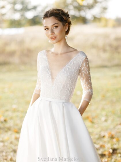 Катарина 1 Svetlana Markelova Это изысканное свадебное платье обладает элегантным А-силуэтом, который создает женственный и романтичный образ невесты. Особое внимание привлекает лиф платья, выполненный из кружева, которое обладает уникальным свойством - светиться в темноте. Этот волшебный эффект придает наряду таинственность и загадочность, будто окутывая невесту сиянием. Юбка платья изготовлена из роскошной парчи, декорированной серебристыми нитями. Эта благородная ткань добавляет образу торжественности и величия. Сочетание сияющего кружева и парчи выглядит поистине роскошно. Игра света и фактур, благородные материалы и безупречный крой - все это делает этот наряд по-настоящему уникальным и запоминающимся.