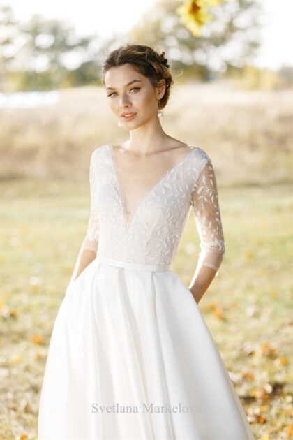 Катарина 1 Svetlana Markelova Это изысканное свадебное платье обладает элегантным А-силуэтом, который создает женственный и романтичный образ невесты. Особое внимание привлекает лиф платья, выполненный из кружева, которое обладает уникальным свойством - светиться в темноте. Этот волшебный эффект придает наряду таинственность и загадочность, будто окутывая невесту сиянием. Юбка платья изготовлена из роскошной парчи, декорированной серебристыми нитями. Эта благородная ткань добавляет образу торжественности и величия. Сочетание сияющего кружева и парчи выглядит поистине роскошно. Игра света и фактур, благородные материалы и безупречный крой - все это делает этот наряд по-настоящему уникальным и запоминающимся.