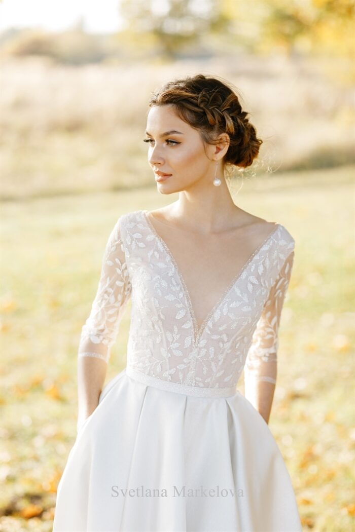 Катарина 1 Svetlana Markelova Это изысканное свадебное платье обладает элегантным А-силуэтом, который создает женственный и романтичный образ невесты. Особое внимание привлекает лиф платья, выполненный из кружева, которое обладает уникальным свойством - светиться в темноте. Этот волшебный эффект придает наряду таинственность и загадочность, будто окутывая невесту сиянием. Юбка платья изготовлена из роскошной парчи, декорированной серебристыми нитями. Эта благородная ткань добавляет образу торжественности и величия. Сочетание сияющего кружева и парчи выглядит поистине роскошно. Игра света и фактур, благородные материалы и безупречный крой - все это делает этот наряд по-настоящему уникальным и запоминающимся.