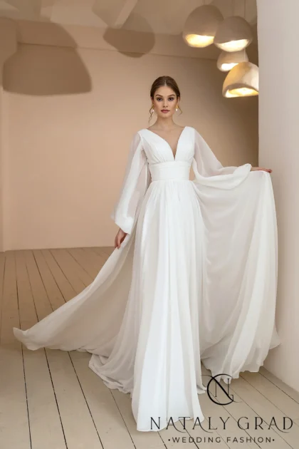 Кларис 1 Nataly Grad <p style="text-align: justify;">Это платье создает невероятно нежный и женственный образ для невесты. Легкий и воздушный шифон струится вокруг фигуры, подчеркивая ее изящность. Силуэт в форме буквы «А» визуально вытягивает и стройнит силуэт, придавая образу элегантность и утонченность. Мягкие драпировки и плавные линии делают движения невесты плавными и грациозными. Интересным акцентом в этом платье является фатин с деликатным блестящим напылением. Он словно покрывает наряд мерцающей дымкой, создавая ощущение магии и сказочности. Сочетание нежного шифона, элегантного А-силуэта и искристого фатина рождает по-настоящему романтичный и возвышенный образ невесты. Этот наряд будет великолепно смотреться как на торжественной церемонии, так и на фотосессии, подчеркивая природную красоту и грациозность его обладательницы.</p>