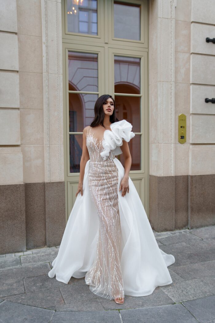 Аронди - Сонеста Аронди 1 Сонеста <p style="text-align: justify;">Свадебное платье трансформер облегающего силуэта с съемной юбкой и объемным декором на плече — это находка для невесты, которая хочет сочетать в своем образе элегантность и креативность. Облегающий силуэт выгодно подчеркивает фигуру, а съемная юбка предоставляет возможность легко изменить стиль наряда в течение дня. Объемный декор на плече изящно завершает образ, придавая ему уникальность и оригинальность. Основной материал — фатин, который обеспечивает легкость и воздушность, в сочетании с глиттером, добавляющим блеска и шика, делает платье особенно привлекательным. Этот наряд станет идеальным выбором для современных свадеб, где невеста может продемонстрировать свою индивидуальность и стиль.</p>
<iframe src="https://www.youtube.com/embed/ZD-GBAdhLmc" width="auto" height="600" frameborder="0" allowfullscreen="allowfullscreen"></iframe>