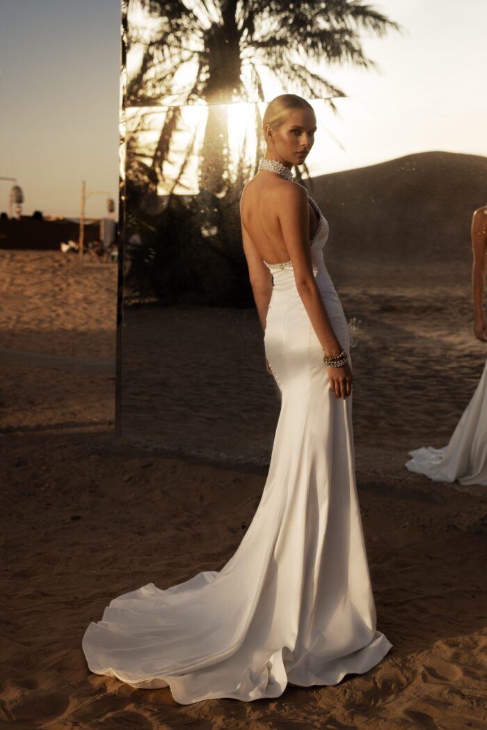 Эйлид 3 Наталья Романова <p style="text-align: justify;">Свадебное платье облегающего силуэта с американской проймой и открытой спиной — невероятно стильный и соблазнительный выбор для невесты.
Американская пройма подчеркивает плечи и придает образу выразительности, а открытая спина добавляет нотку игривости и женственности. Воротник и корсет, расшитые жемчужинами, придают наряду роскошный вид и демонстрируют внимание к деталям.
Основной материал — тонкий атлас — делает платье комфортным и приятным на ощупь, а также создает роскошное сияние, которое будет эффектно переливаться в свете. Это платье идеально подойдет для невест, желающих сочетать элегантность с модернистским стилем, создавая запоминающийся образ.
Модель доступна в размере плюс сайз.</p>
<iframe id="video-iframe" src="https://www.youtube.com/embed/bgxvYJbp2cE" width="auto" height="600" frameborder="0" allowfullscreen="allowfullscreen"></iframe>