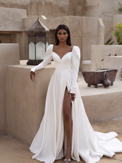 Ирелия 1 Наталья Романова <p style="text-align: justify;">Свадебное платье А-силуэта с длинными рукавами и открытой спиной — это элегантный и романтичный выбор для невесты. А-силуэт великолепно подходит для большинства типов фигур, создавая плавные линии и подчеркивая талию.
Длинные рукава придают образу утонченность, а открытая спина добавляет нотку сексуальности и эффекта неожиданности. Разрез в юбке акцентирует ноги и придаёт образу динамичность, позволяя удобно двигаться.
Основной материал — микадо — обеспечивает платью роскошный вид и структуру, прекрасно удерживая форму. Этот вечерний наряд идеально подходит как для церемонии, так и для вечернего праздника, создавая стильный и запоминающийся образ для невесты.
Модель доступна в размере плюс сайз.</p>
<iframe id="video-iframe" src="https://www.youtube.com/embed/MP2U4NTr5qM" width="auto" height="600" frameborder="0" allowfullscreen="allowfullscreen"></iframe>