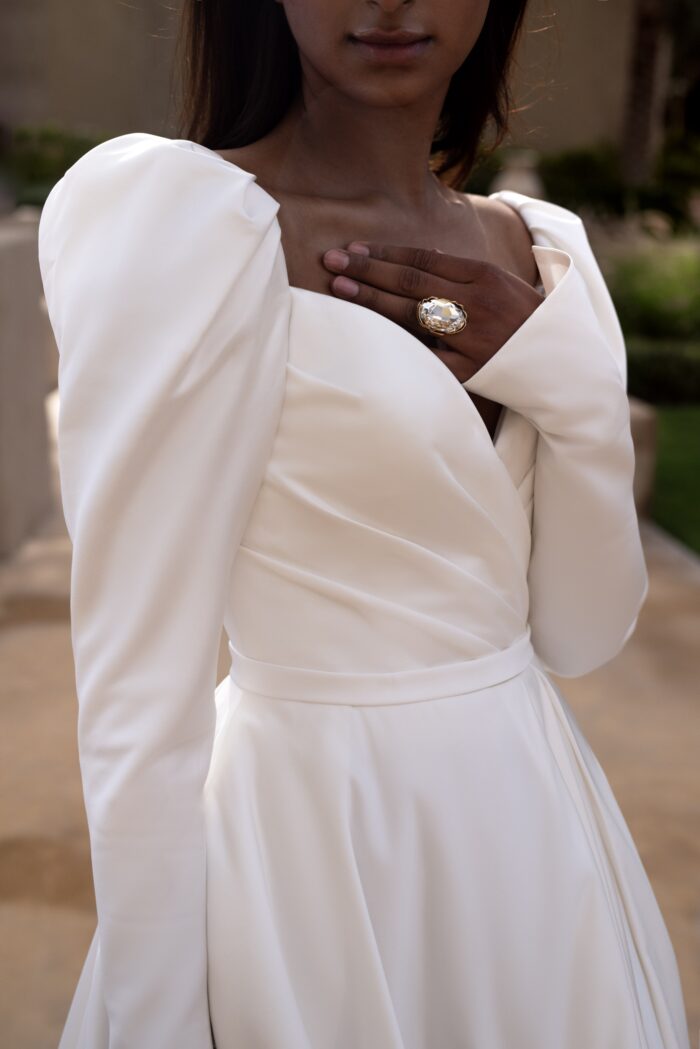 Ирелия - Наталья Романова Ирелия 5 Наталья Романова <p style="text-align: justify;">Свадебное платье А-силуэта с длинными рукавами и открытой спиной — это элегантный и романтичный выбор для невесты. А-силуэт великолепно подходит для большинства типов фигур, создавая плавные линии и подчеркивая талию.
Длинные рукава придают образу утонченность, а открытая спина добавляет нотку сексуальности и эффекта неожиданности. Разрез в юбке акцентирует ноги и придаёт образу динамичность, позволяя удобно двигаться.
Основной материал — микадо — обеспечивает платью роскошный вид и структуру, прекрасно удерживая форму. Этот вечерний наряд идеально подходит как для церемонии, так и для вечернего праздника, создавая стильный и запоминающийся образ для невесты.
Модель доступна в размере плюс сайз.</p>
<iframe id="video-iframe" src="https://www.youtube.com/embed/MP2U4NTr5qM" width="auto" height="600" frameborder="0" allowfullscreen="allowfullscreen"></iframe>