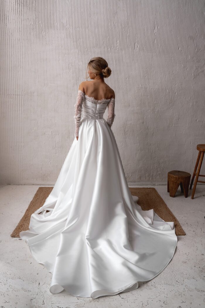 Наила 1 Наталья Романова <p style="text-align: justify;">Свадебное платье А-силуэта с длинными рукавами и разрезом в юбке — это прекрасный выбор для невесты, которая хочет сочетать элегантность и романтичность.
Длинные рукава, изготовленные из тонкого вышитого кружева шантильи, добавляют платью утонченности и женственности. Это кружево прекрасно вбирает в себя свет и создает эффектный визуальный контраст с основным материалом — микадо. Корсет из кружева подчеркивает талию и создает изящный силуэт.
Разрез в юбке не только придаёт наряду динамичность, но и обеспечивает комфорт при движении. Такой элемент делает образ более современным и смелым.
Эта модель будет отлично смотреться как на церемонии, так и на вечернем празднике, превращая невесту в королеву вечера.
Модель доступна в размере плюс сайз.</p>
<iframe id="video-iframe" src="https://www.youtube.com/embed/2OrRViw-tQI" width="auto" height="600" frameborder="0" allowfullscreen="allowfullscreen"></iframe>