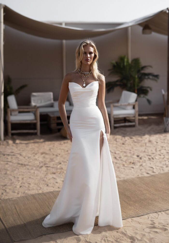 Нами - Наталья Романова Нами 1 Наталья Романова <p style="text-align: justify;">Свадебное платье облегающего силуэта с разрезом в юбке и съемными бретелями — это смелый и стильный выбор для невесты, желающей выделиться в день своей свадьбы.
Облегающий силуэт подчеркивает фигуру, создавая элегантный и утончённый образ, в то время как пышная юбка добавляет наряду объем и придаёт ему романтичную нотку. Разрез в юбке создает эффект движения и придаёт образу динамичность, что делает его ещё более привлекательным.
Съемные бретели позволяют легко менять стиль платья в зависимости от настроения и формата мероприятия. Это добавляет универсальности, позволяя невесте ощутить себя как в классическом, так и в более современном облачении.
Основной материал — микадо — известен своей прочностью и прелестным блеском, что делает платье не только стильным, но и комфортным. Это платье идеально подойдет как для торжественной церемонии, так и для вечернего праздника, создавая незабываемый образ для невесты.
Модель доступна в размере плюс сайз.</p>
<iframe id="video-iframe" src="https://www.youtube.com/embed/gHbQFSbu1Lc" width="auto" height="600" frameborder="0" allowfullscreen="allowfullscreen"></iframe>