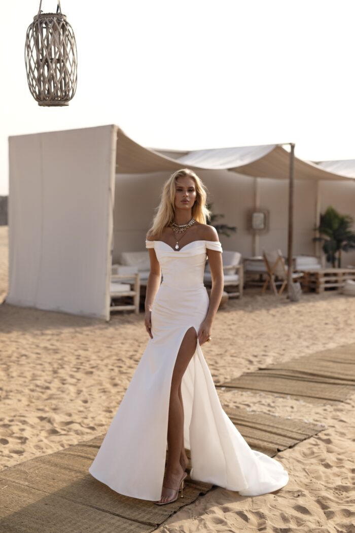 Нами - Наталья Романова Нами 2 Наталья Романова <p style="text-align: justify;">Свадебное платье облегающего силуэта с разрезом в юбке и съемными бретелями — это смелый и стильный выбор для невесты, желающей выделиться в день своей свадьбы.
Облегающий силуэт подчеркивает фигуру, создавая элегантный и утончённый образ, в то время как пышная юбка добавляет наряду объем и придаёт ему романтичную нотку. Разрез в юбке создает эффект движения и придаёт образу динамичность, что делает его ещё более привлекательным.
Съемные бретели позволяют легко менять стиль платья в зависимости от настроения и формата мероприятия. Это добавляет универсальности, позволяя невесте ощутить себя как в классическом, так и в более современном облачении.
Основной материал — микадо — известен своей прочностью и прелестным блеском, что делает платье не только стильным, но и комфортным. Это платье идеально подойдет как для торжественной церемонии, так и для вечернего праздника, создавая незабываемый образ для невесты.
Модель доступна в размере плюс сайз.</p>
<iframe id="video-iframe" src="https://www.youtube.com/embed/gHbQFSbu1Lc" width="auto" height="600" frameborder="0" allowfullscreen="allowfullscreen"></iframe>