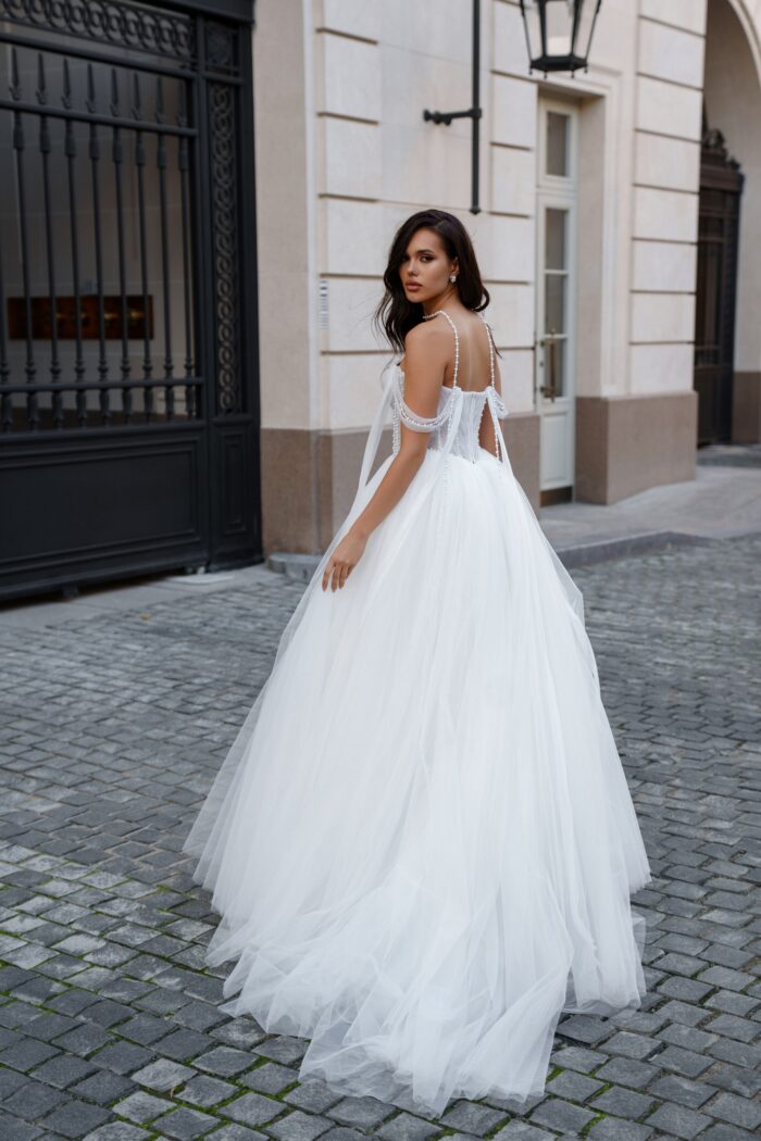 Оберон - Сонеста Оберон 2 Сонеста <p style="text-align: justify;">Свадебное платье А-силуэта с драпированным корсетом и жемчужинами — это наряд, который сочетает в себе романтичность и элегантность. А-силуэт имеет утонченную форму, которая подходит многим типам фигур, плавно очерчивая линии тела и создавая эффект легкости.
Драпированный корсет украшен жемчужинами, что добавляет платью роскоши и блеска. Драпировка создает красивые складки, подчеркивающие линию талии и придающие образу текстурное разнообразие. Жемчужины добавляют яркости и изысканности, превращая ткань в настоящий фокус внимания.
Основной материал — фатин, известный своей воздушностью и легкостью, создает ощущение романтики и невесомости. Он придает платью объем и структуру, позволяя юбке красиво ложиться и драпироваться.
Сотуар для шеи, предлагаемый в комплекте (продается отдельно), станет отличным дополнением к образу и поможет подчеркнуть красоту neckline. Это украшение поможет создать завершенный вид, добавляя нотку шикарности и утонченности.</p>
<iframe src="https://www.youtube.com/embed/-qiz6TV5XJs" width="auto" height="600" frameborder="0" allowfullscreen="allowfullscreen"></iframe>