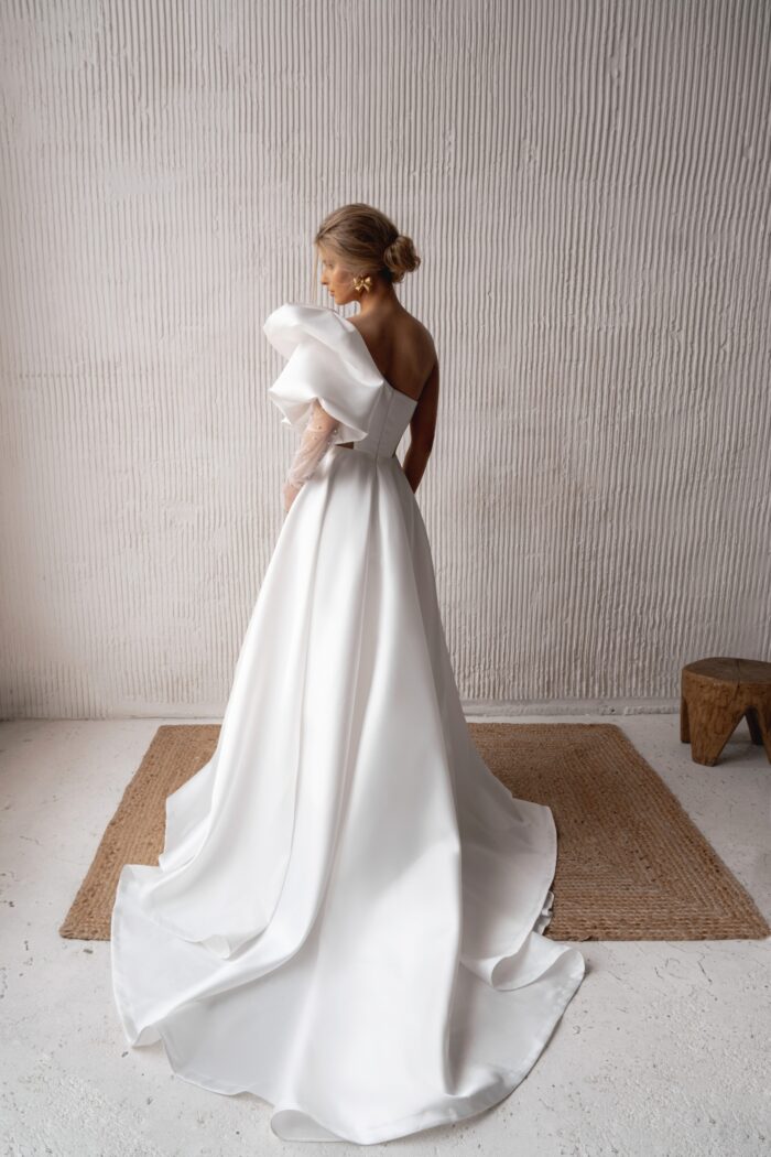 Савия 2 Наталья Романова <p style="text-align: justify;">Свадебное платье А-силуэта с одним объемным рукавом, разрезом в юбке и телесными вставками на талии — это стильный и смелый выбор для невесты, желающей выделиться.
Объемный рукав придает драматичность, а разрез в юбке добавляет игривости и облегчает движение. Телесные вставки на талии создают эффект струящегося силуэта, подчеркивая женственность.
Изготовленное из микадо, платье обладает структурой и блеском, что делает его идеальным выбором для свадебного праздника. Это наряд для современных невест, стремящихся к уникальности и элегантности в своем образе.
Модель доступна в размере плюс сайз.</p>
<iframe id="video-iframe" src="https://www.youtube.com/embed/hehH5yVQ5KM" width="auto" height="600" frameborder="0" allowfullscreen="allowfullscreen"></iframe>