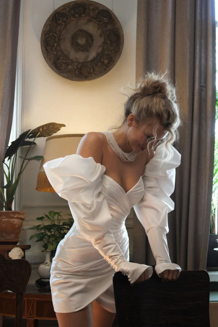 Симфони 2 Наталья Романова <p style="text-align: justify;">Короткое свадебное платье с длинными объемными рукавами и открытой спиной. Объемные рукава создают романтичный вид, придавая платью выразительность и стильный акцент.
Открытая спина на молнии добавляет нотку свежести и современности, подчеркивая силуэт и придавая образу сексуальность в сочетании с элегантностью. Это сочетание элементов делает платье идеальным для свадеб, где невеста хочет выделяться и оставлять незабываемое впечатление.
Основной материал — тафта — отличный выбор для такого наряда, так как она обладает великолепной структурой и легким блеском. Тафта добавляет платью форму и объем, создавая красивое движение и драпировку.
Это платье станет замечательным выбором для невесты, желающей сочетать шик и комфорт, предоставляя возможность выразить свою индивидуальность.
Модель доступна в размере плюс сайз.</p>
