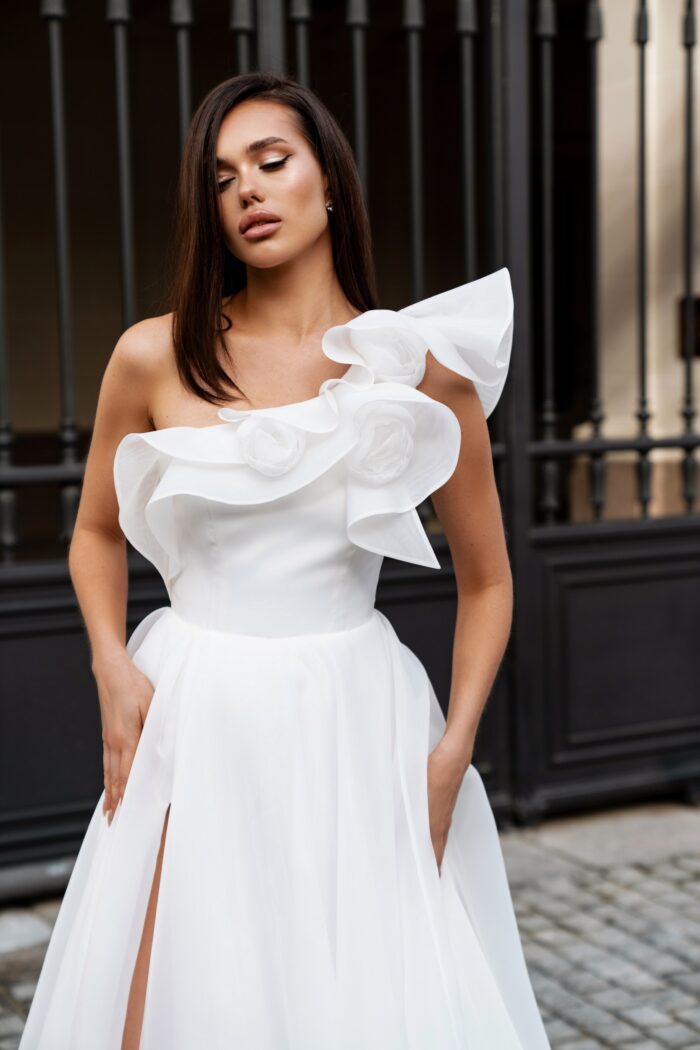 Вистерия 7 Сонеста <p style="text-align: justify;">Свадебное платье А-силуэта с одной бретелью и декором из роз ручной работы — это образец романтичности и современного стиля, который привлекает внимание и подчеркивает индивидуальность невесты. А-силуэт создает эффект легкости и воздушности, идеально подходя для создания изысканного образа.
Одно плечо открывает шею и плечо, добавляя нотку чувственности и элегантности, в то время как ручные розы служат великолепным акцентом, придающим платью уникальность и изящество. Декор из роз создает романтический настрой и отлично гармонирует с свадебной тематикой.
Основной материал — органза, известная своей легкостью и полупрозрачностью, создает эффект нежности и воздушности, а также добавляет объема юбке. Такое платье станет прекрасным выбором для летней или весенней свадьбы, подчеркивая красоту невесты. Оно станет идеальным фоном для счастья и любви, а детали ручной работы сделают образ по-настоящему уникальным.</p>
<iframe src="https://www.youtube.com/embed/ZoYVJEeM9FI" width="auto" height="600" frameborder="0" allowfullscreen="allowfullscreen"></iframe>