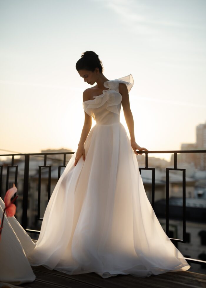 Вистерия 1 Сонеста <p style="text-align: justify;">Свадебное платье А-силуэта с одной бретелью и декором из роз ручной работы — это образец романтичности и современного стиля, который привлекает внимание и подчеркивает индивидуальность невесты. А-силуэт создает эффект легкости и воздушности, идеально подходя для создания изысканного образа.
Одно плечо открывает шею и плечо, добавляя нотку чувственности и элегантности, в то время как ручные розы служат великолепным акцентом, придающим платью уникальность и изящество. Декор из роз создает романтический настрой и отлично гармонирует с свадебной тематикой.
Основной материал — органза, известная своей легкостью и полупрозрачностью, создает эффект нежности и воздушности, а также добавляет объема юбке. Такое платье станет прекрасным выбором для летней или весенней свадьбы, подчеркивая красоту невесты. Оно станет идеальным фоном для счастья и любви, а детали ручной работы сделают образ по-настоящему уникальным.</p>
<iframe src="https://www.youtube.com/embed/ZoYVJEeM9FI" width="auto" height="600" frameborder="0" allowfullscreen="allowfullscreen"></iframe>