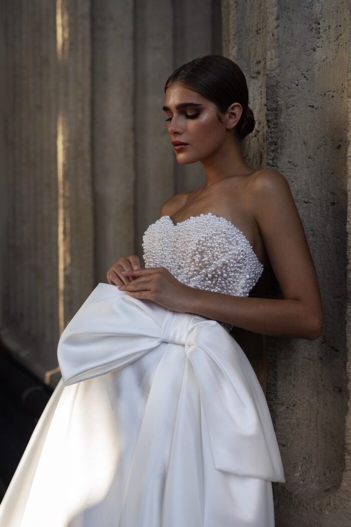 Дора 1 Патрисия Кутюр <p style="text-align: justify;">Дополненное расшитым жемчугом боди с длинными рукавами, платье создает эффектный и стильный силуэт, который отлично подходит для невест, предпочитающих более классический и романтичный стиль. Пышная юбка придаёт образу объём и легкость, а декоративный бант добавляет нотку игривости и оригинальности.
Основной материал микадо обеспечивает не только шикарный внешний вид, но и комфорт в носке. Это платье идеально подойдет для торжественной и запоминающейся свадьбы, представляя собой великолепный баланс между традициями и современными тенденциями.</p>
<iframe src="https://www.youtube.com/embed/G7xB1fQ8z3E" width="auto" height="600" frameborder="0" allowfullscreen="allowfullscreen"></iframe>