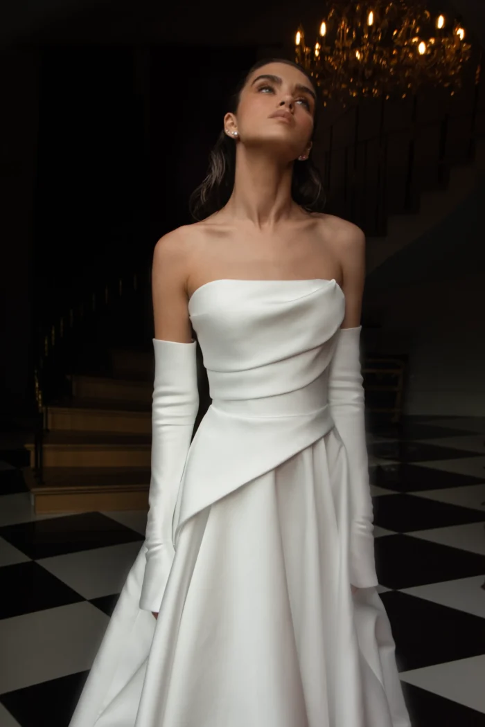 Лебрен 1 Наталья Романова <p style="text-align: justify;">Элегантное свадебное платье А‑силуэта из благородного микадо с асимметрией на линии талии. Образ дополняют съёмные перчатки, позволяющие легко менять стиль — от утончённой классики до современного акцента.</p>
<iframe src="https://www.youtube.com/embed/vQrdOl8Jdzo" width="auto" height="600" frameborder="0" allowfullscreen="allowfullscreen"></iframe>